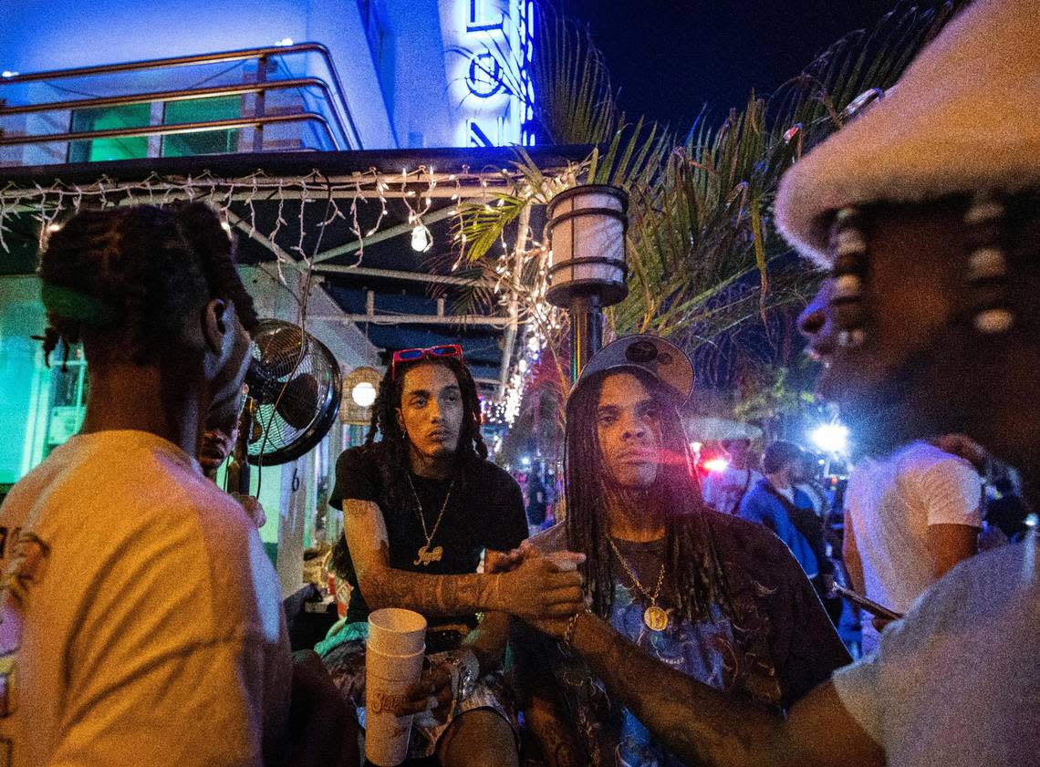 Chris, left, and Kris Johnson, center, from New York, shake hands with a Miami local during spring break on Sunday, March 17, 2024, on Ocean Drive in South Beach.