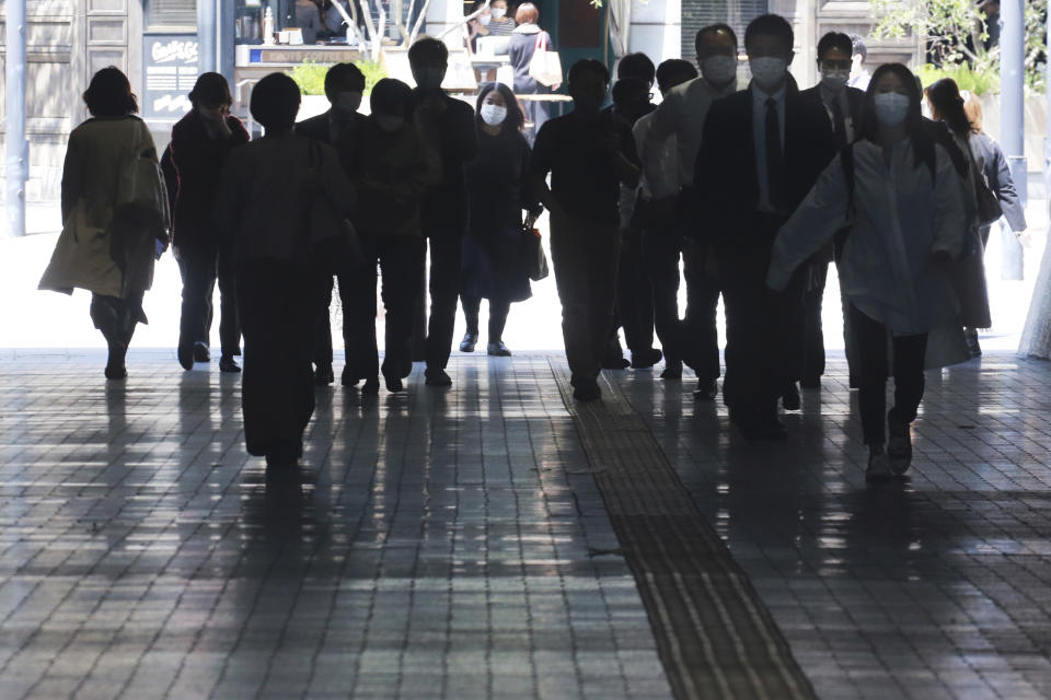 People wearing face masks to protect against the spread of the coronavirus walk on an underpass in Tokyo, Monday, April 12, 2021. Japan started its vaccination drive with medical workers and expanded Monday to older residents, with the first shots being given in about 120 selected places around the country. (AP Photo/Koji Sasahara)