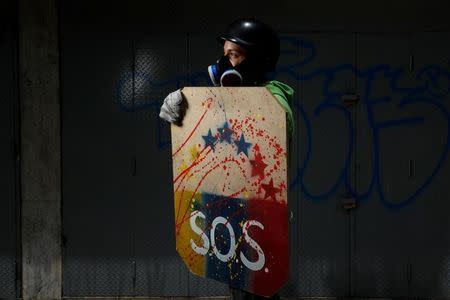 A demonstrator holding a rudimentary shield poses for a picture before a rally against Venezuelan President Nicolas Maduro's government in Caracas, Venezuela, May 27, 2017. REUTERS/Carlos Garcia Rawlins