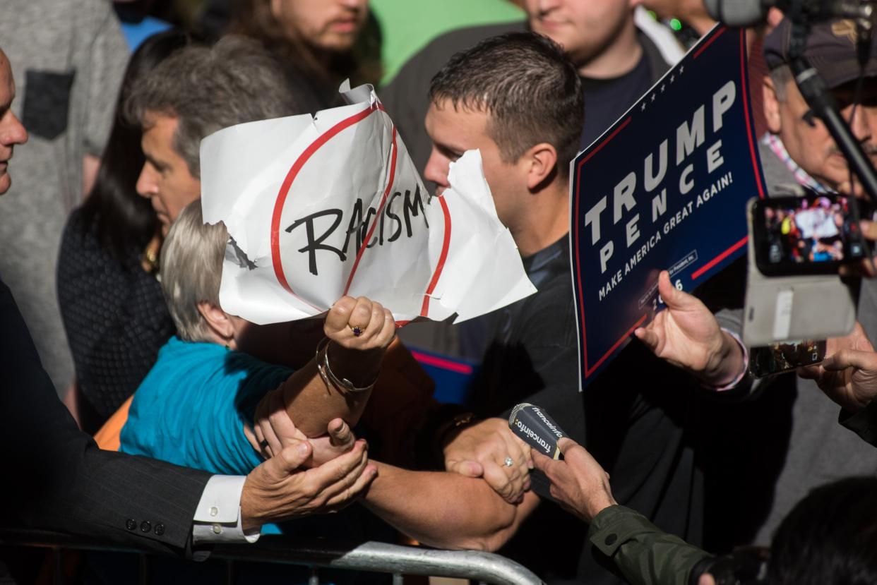 A protester with an anti-racism sign is confronted and removed from a rally for Republican Presidential candidate Donald J. Trump at the McGrath Amphitheater on October 28, 2016 in Cedar Rapids, Iowa. The state’s governor has signed a bill cracking down on crimes associated with protests (Getty Images)