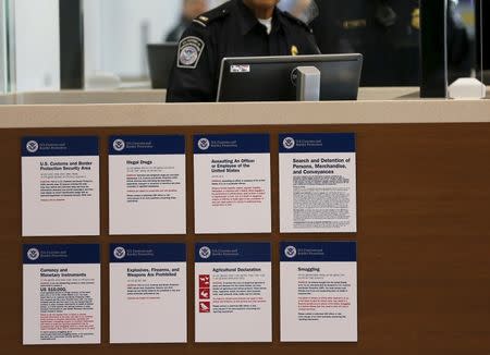 U.S. Customs and Immigration officers await travelers during the opening day of the Cross Border Xpress pedestrian bridge between San Diego and the Tijuana airport on the facility's opening day in Otay Mesa, California December 9, 2015. The privately run facility allows ticketed passengers to skip long border waits and clear U.S. Customs for a fee. REUTERS/Mike Blake - RTX1XYZH