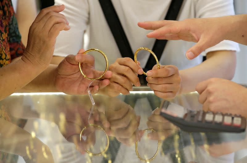 FILE PHOTO: Customers select gold bracelets at Caibai Jewelry store in Beijing
