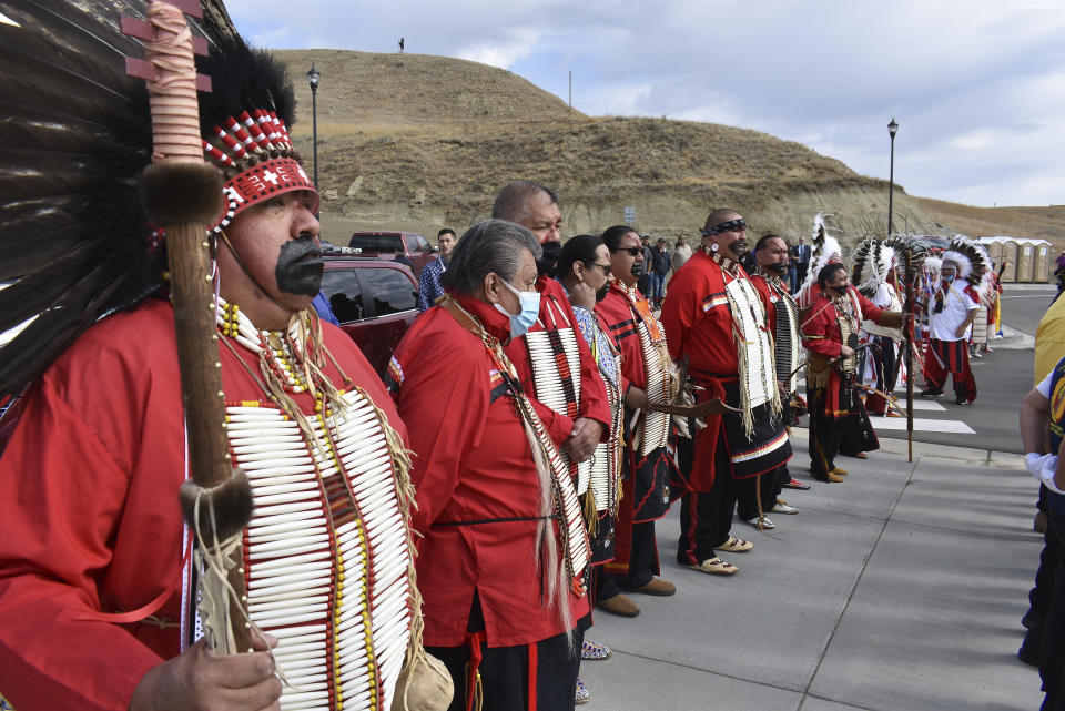 In this Wednesday, May 19, 2021, photo, members of the Black Mouth Society, a traditional group on the Fort Berthold Indian Reservation line up at an event marking the opening of the MHA Nation Interpretive Center, a cultural center and museum in New Town, North Dakota. Oil pumped from Native American lands in the U.S. increased almost tenfold since 2009 to more than 130 million barrels annually, bringing new wealth to a handful of tribes. Other tribes left out of the drilling boom have become increasingly outspoken against fossil fuels as climate change’s impacts grow worse. (AP Photo/Matthew Brown)