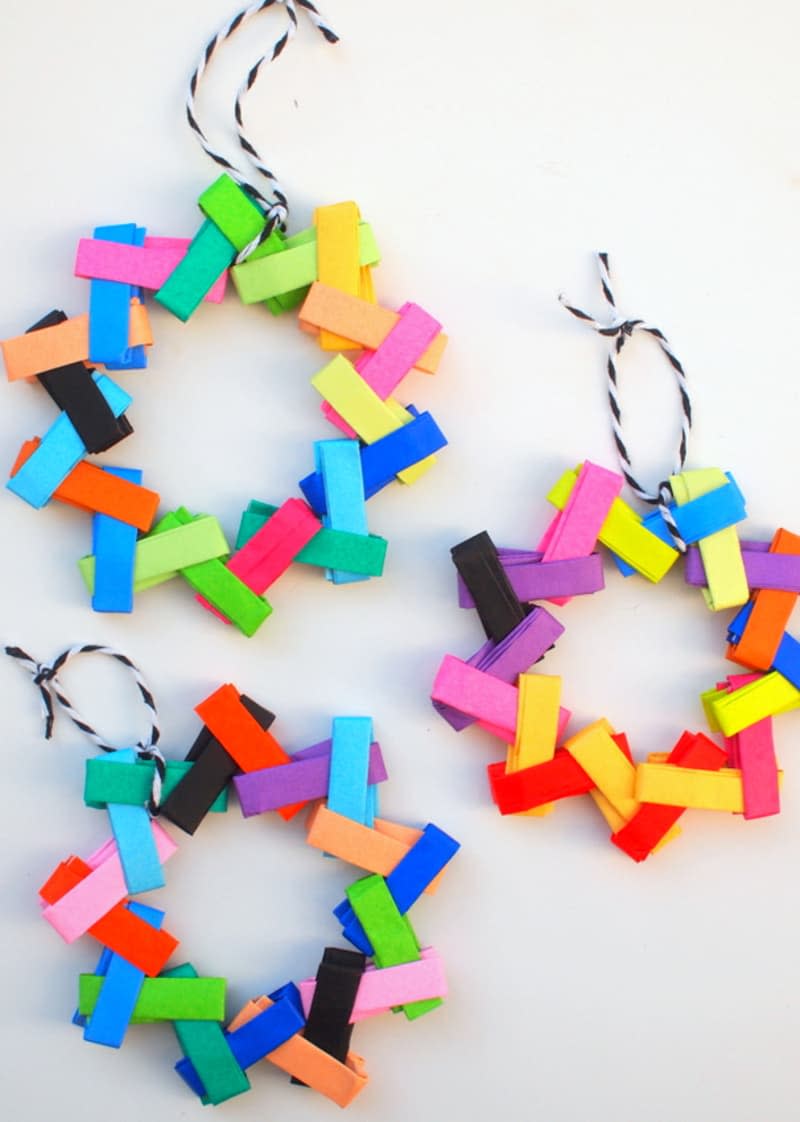 Three multicolored origami wreaths made of paper chains arranged in circles and attached to a string for hanging