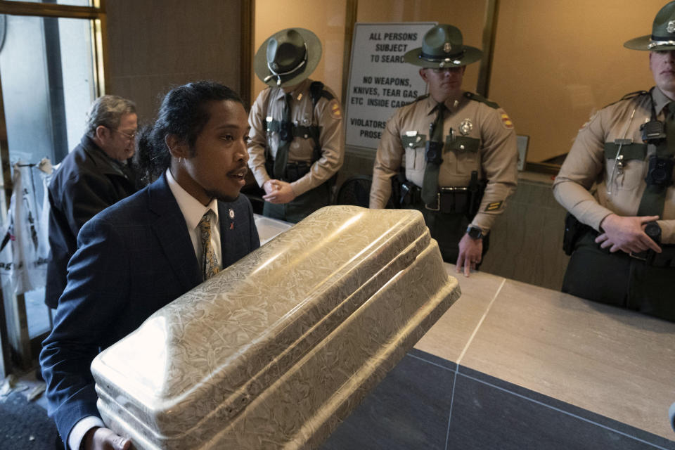 Rep. Justin Jones, D-Nashville, carries a child's casket into the state Capitol past state troopers, Monday, April 17, 2023, in Nashville, Tenn. (AP Photo/George Walker IV)