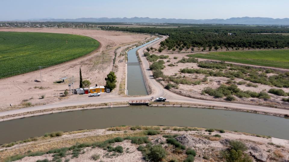El canal de riego principal del distrito de Delicias, en primer plano, se conecta con un canal más pequeño. El agua del río Conchos alimenta la producción de alfalfa y nueces pecanas en agosto de 2023.
