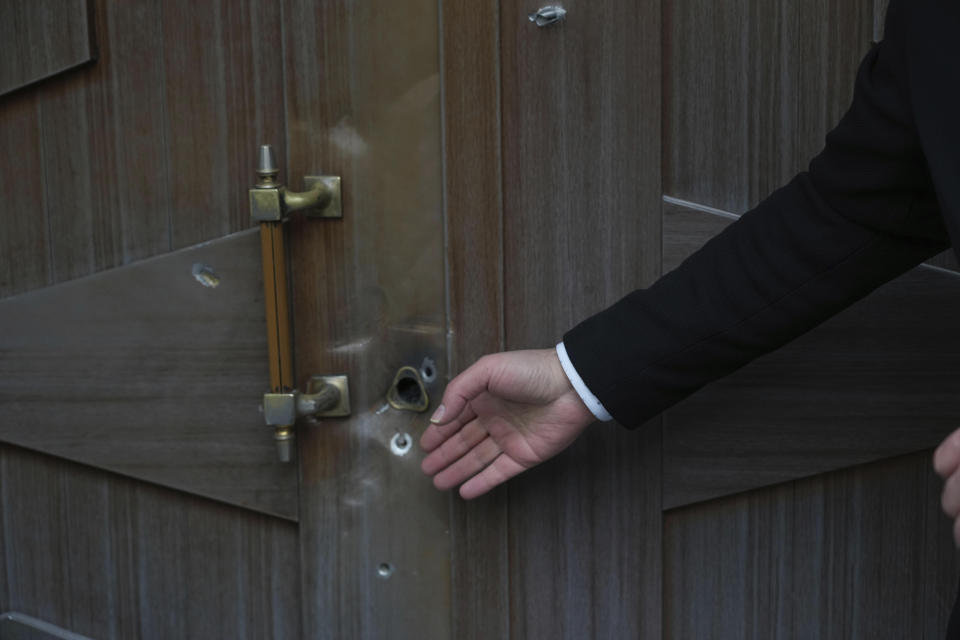 A man gestures at bullet holes left after an attack at the Azerbaijan Embassy in Tehran, Iran, Friday, Jan. 27, 2023. A man armed with a Kalashnikov-style rifle stormed the Azerbaijan Embassy in Iran's capital Friday, killing the head of security at the diplomatic post and wounding two guards, authorities said. (AP Photo/Vahid Salemi)