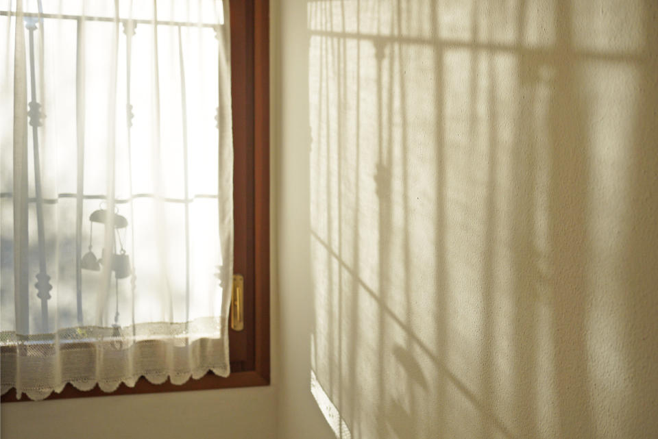 Sun filtering through window designing geometrical pattern on opposite wall.