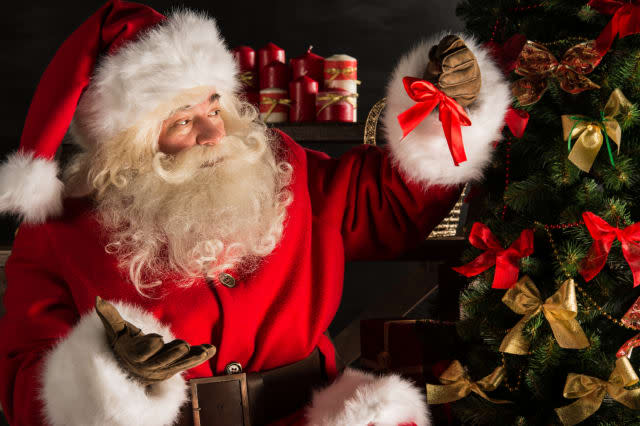 Santa Claus decorating Christmas tree in dark room