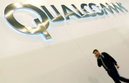 FILE PHOTO: A man walks past a Qualcomm advertising logo at the Mobile World Congress at Barcelona, February 27, 2013. REUTERS/Albert Gea/File Photo