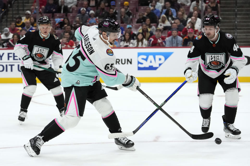 Pacific Division's Erik Karlsson, of the San Jose Sharks (65) shoots as Central Division's Josh Morrissey, of the Winnipeg Jets (44) defends during the NHL All Star hockey game, Saturday, Feb. 4, 2023, in Sunrise, Fla. (AP Photo/Lynne Sladky)