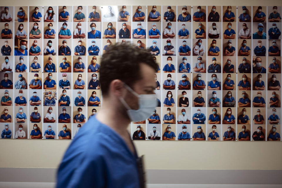 A member of staff passes in front of a collection of portraits of medical staff at Bichat Hospital, AP-HP, in Paris, Thursday, April 22, 2021. France still had nearly 6,000 critically ill patients in ICUs this week as the government embarked on the perilous process of gingerly easing the country out of its latest lockdown, too prematurely for those on pandemic frontlines in hospitals. President Emmanuel Macron's decision to reopen elementary schools on Monday and allow people to move about more freely again in May, even though ICU numbers have remained stubbornly higher than at any point since the pandemic's catastrophic first wave, marks another shift in multiple European capitals away from prioritizing hospitals. (AP Photo/Lewis Joly)