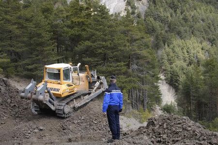 French Gendarme Bruno Hermignies stands by a bulldozer clearing a path to the crash site of the Germanwings Airbus A320 in the mountains, near Seyne-les-Alpes, French Alps, March 30, 2015. REUTERS/Claude Paris/Pool