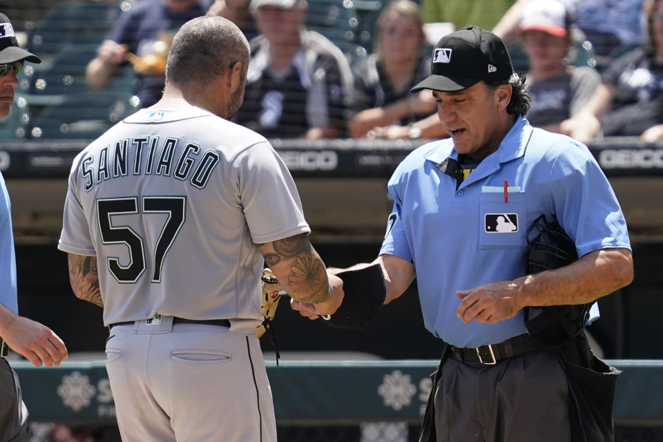 El umpire Phil Cuzzi (derecha) revisa al relevista Héctor Santiago de los Marineros de Seattle, el domingo 27 de junio de 2021. Santiago fue expulsado por Cuzzi. (AP Foto/Nam Y. Huh)