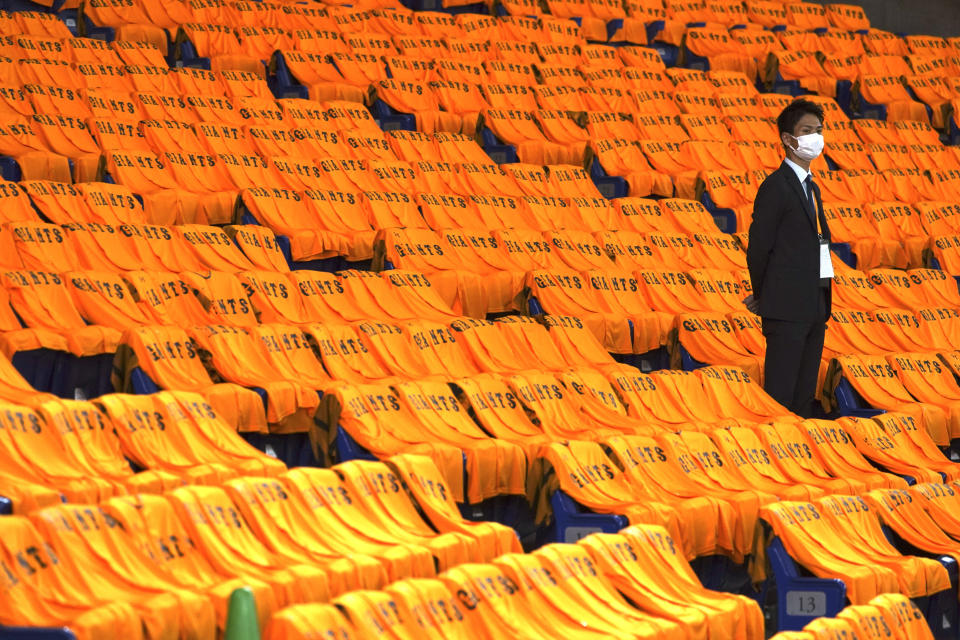 A man stands at the empty seats with orange color jerseys prior to an opening baseball game between the Yomiuri Giants and the Hanshin Tigers at Tokyo Dome in Tokyo Friday, June 19, 2020. Japan's professional baseball regular season will be kicked off Friday without fans in attendance because of the threat of the spreading coronavirus. (AP Photo/Eugene Hoshiko)