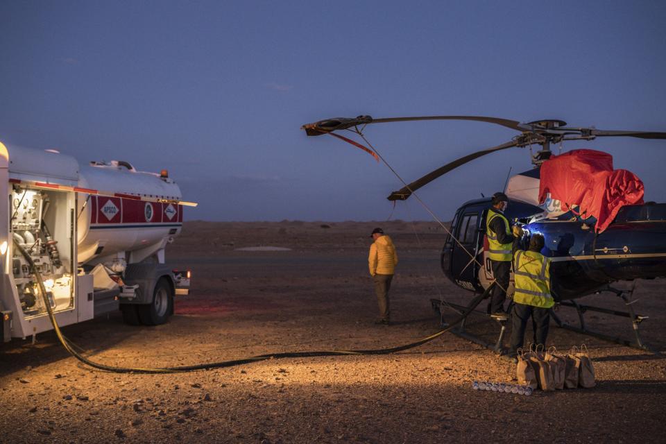 In this Sunday, Jan. 12, 2020 photo, APSCO employees fill a tank of a Dakar helicopter at the end of stage seven in Wadi Al Dawasir, Saudi Arabia. Formerly known as the Paris-Dakar Rally, the race was created by Thierry Sabine after he got lost in the Libyan desert in 1977. Until 2008, the rallies raced across Africa, but threats in Mauritania led organizers to cancel that year's event and move it to South America. It has now shifted to Saudi Arabia. The race started on Jan. 5 with 560 drivers and co-drivers, some on motorbikes, others in cars or in trucks. Only 41 are taking part in the Original category. (AP Photo/Bernat Armangue)