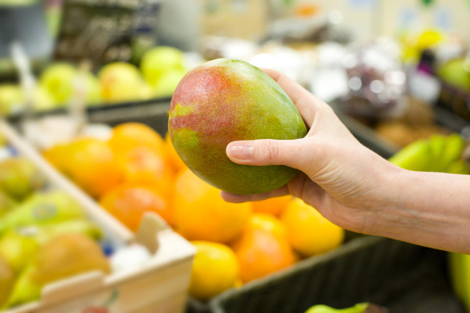 Woman&#39;s hand choosing mango in the market. Concept of healthy food, bio, vegetarian, diet.