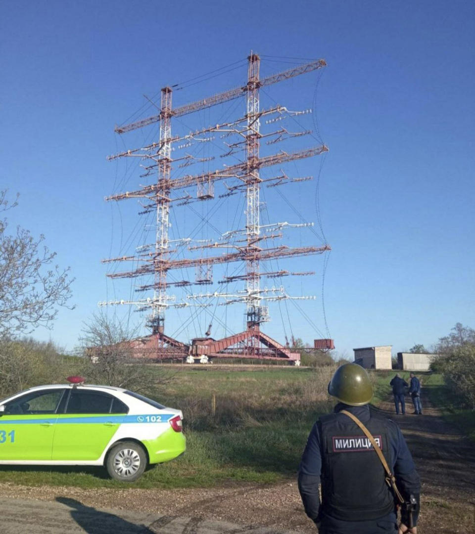 In this photograph released by the Press Center of the Ministry of Internal Affairs of the Pridnestrovian Moldavian Republic, a policeman stands by a radio station in Maiac, in the Moldovan separatist region of Trans-Dniester, Tuesday, April 26, 2022. Police in the Moldovan separatist region of Trans-Dniester say two explosions on Tuesday morning in a radio facility close to the Ukrainian border knocked two powerful antennas out of service just a day after several explosions believed to be caused by rocket-propelled grenades were reported to have hit the Ministry of State Security in the city of Tiraspol, the region's capital (Press Center of the Ministry of Internal Affairs of the Pridnestrovian Moldavian Republic via AP, HO)