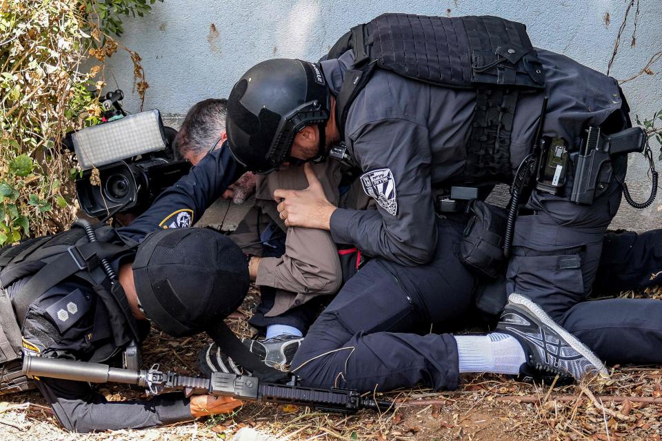 Israeli security forces assist a journalist taking cover during an alert for a rocket attack in Israel's southern city of Sderot near the border with Gaza on October 12, 2023.