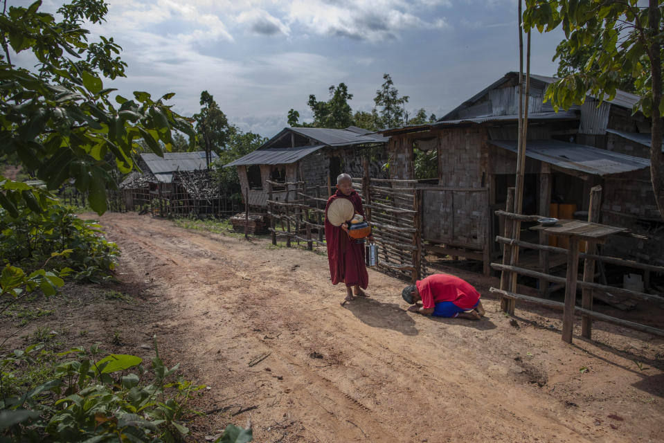 Zin Ko Ko Htwe, who was trafficked twice, bows after offering alms to a Buddhist monk outside his mother's house in Myawaddy, Myanmar, Friday, June 14, 2019. Ko Htwe said after escaping from a fishing boat in 2008, he was sold onto a palm oil plantation run by a police officer in Malaysia. When Americans and Europeans see palm oil is listed as an ingredient in their snacks, they should know "it's the same as consuming our sweat and blood," he says. (AP Photo/Gemunu Amarasinghe)