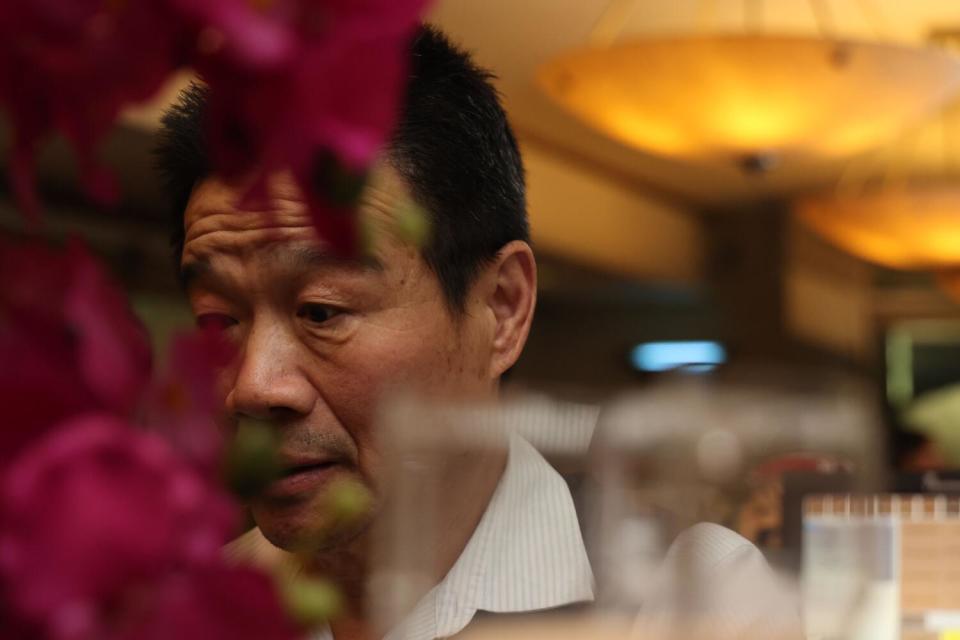 A man, seen in closeup, with a restaurant out of focus behind him