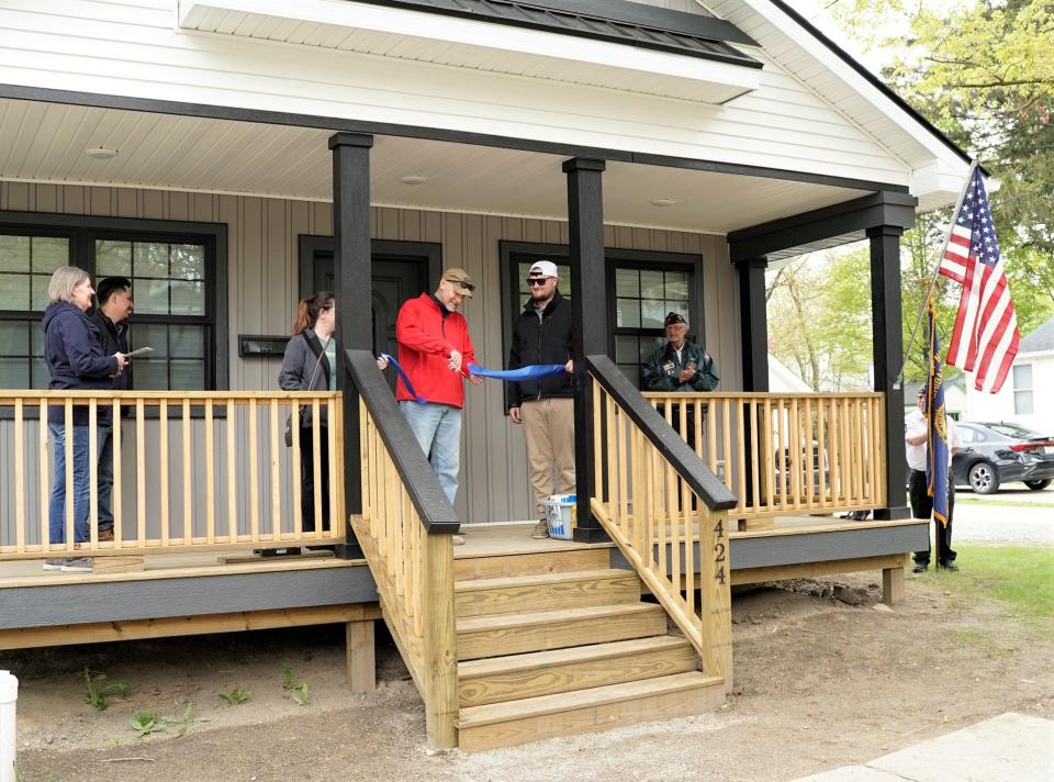New homeowner Tim Brososky, red shirt, cuts the ribbon to his new Habitat for Humanity of Lenawee County house during a dedication ceremony Monday in Adrian.