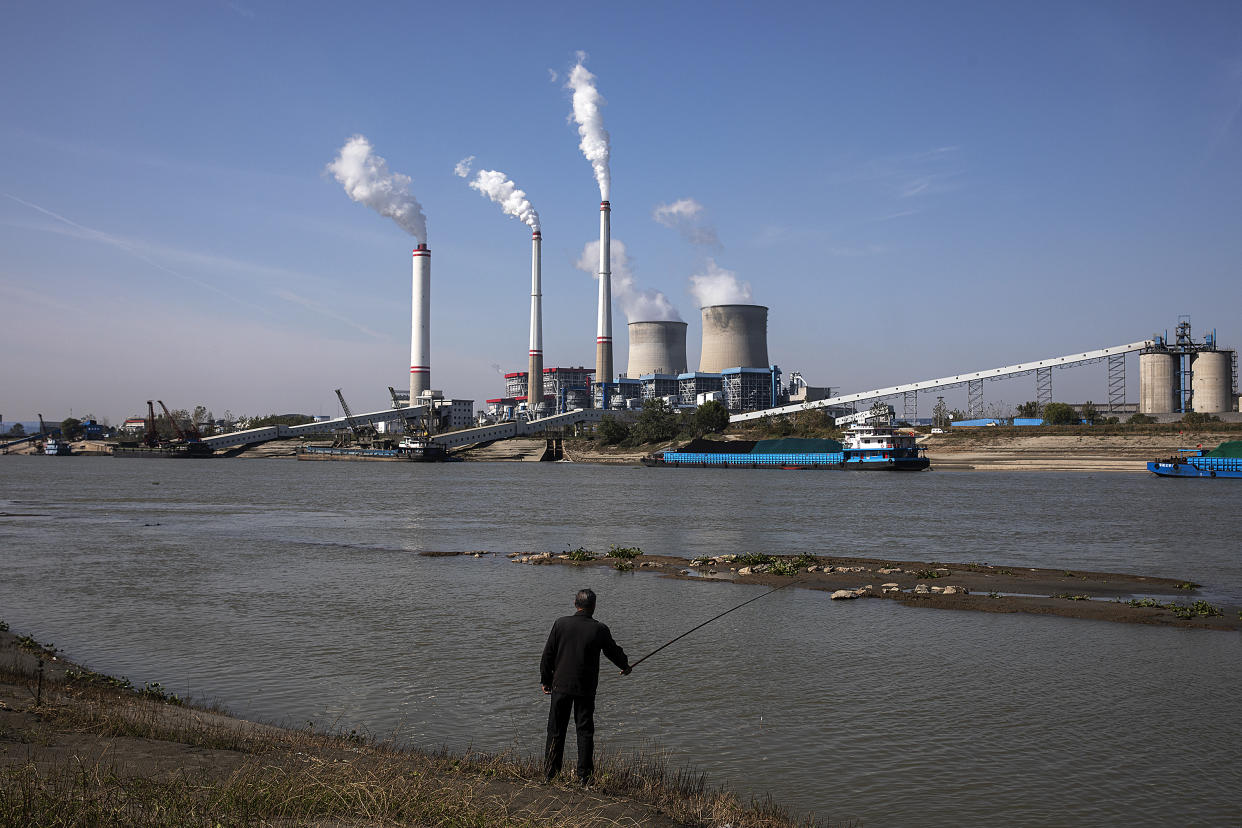 A resident fishes as coal fired power plant is in operation on November 11, 2021 in Hanchuan, Hubei province, China. (Stringer/Getty Images)