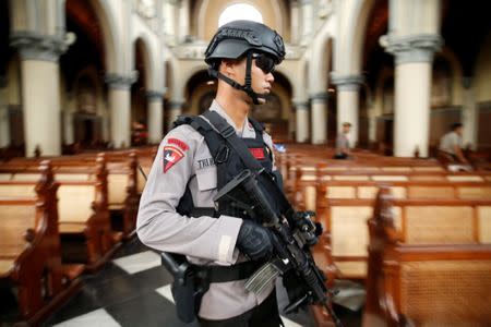 A policeman holds a rifle as he checks inside the Jakarta Cathedral ahead of Christmas celebrations in Indonesia, December 24, 2016. REUTERS/Beawiharta