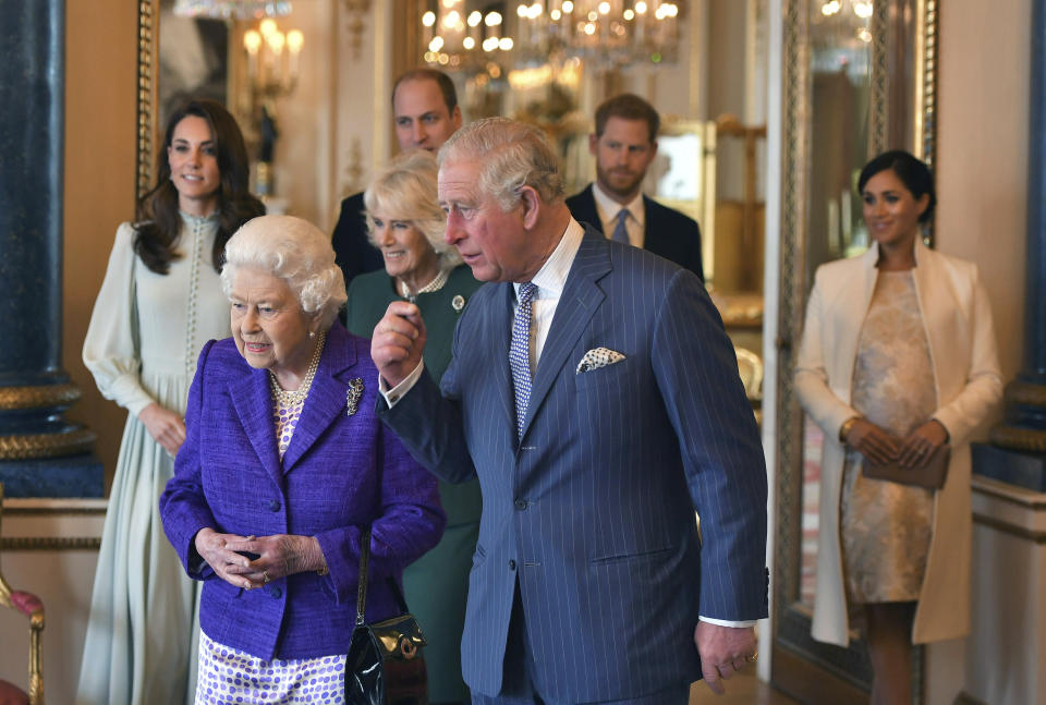 FILE - Britain's Queen Elizabeth II is joined by Prince Charles, the Prince of Wales, and at rear, from left, Kate, Duchess of Cambridge, Camilla, Duchess of Cornwall, Prince William, Prince Harry and Meghan, Duchess of Sussex during a reception at Buckingham Palace, London to mark the 50th anniversary of the investiture of the Prince of Wales, March 5, 2019. (Dominic Lipinski/Pool via AP, File)