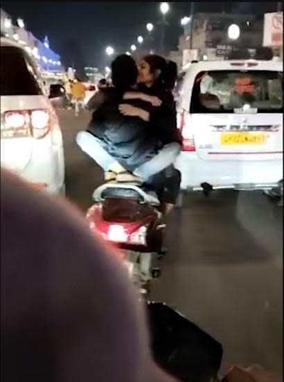 機車騎士騎車時，女友正面緊抱他還熱情擁吻。（翻攝Youtube頻道「Indian Journo」）