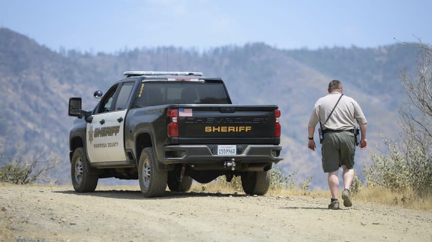 A Mariposa County deputy sheriff stands near the area where a family and their dog were reportedly found dead the day before