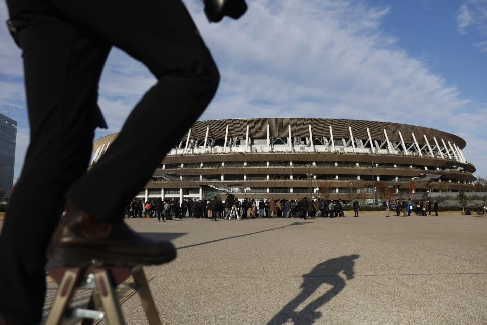 A photographer stands on a step stool to photograph the new National Stadium Sunday, Dec. 15, 2019, in Tokyo. The stadium is officially completed. (AP Photo/Jae C. Hong)