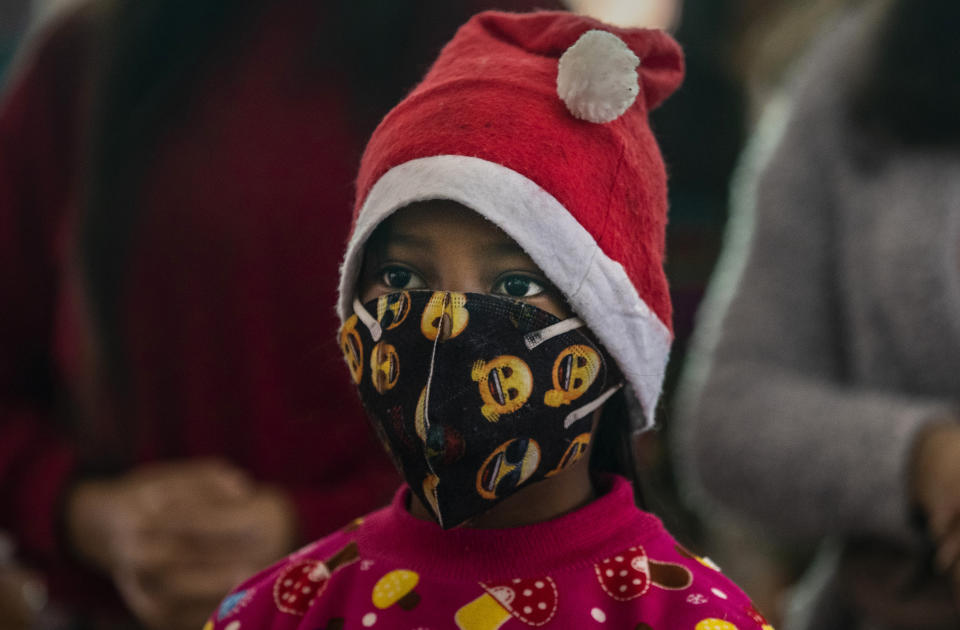 An Indian Christian girl wearing a Santa cap and a face mask as a precaution against the coronavirus attends the Christmas mass at a church in Gauhati, India, Friday, Dec. 25, 2020. (AP Photo/Anupam Nath)