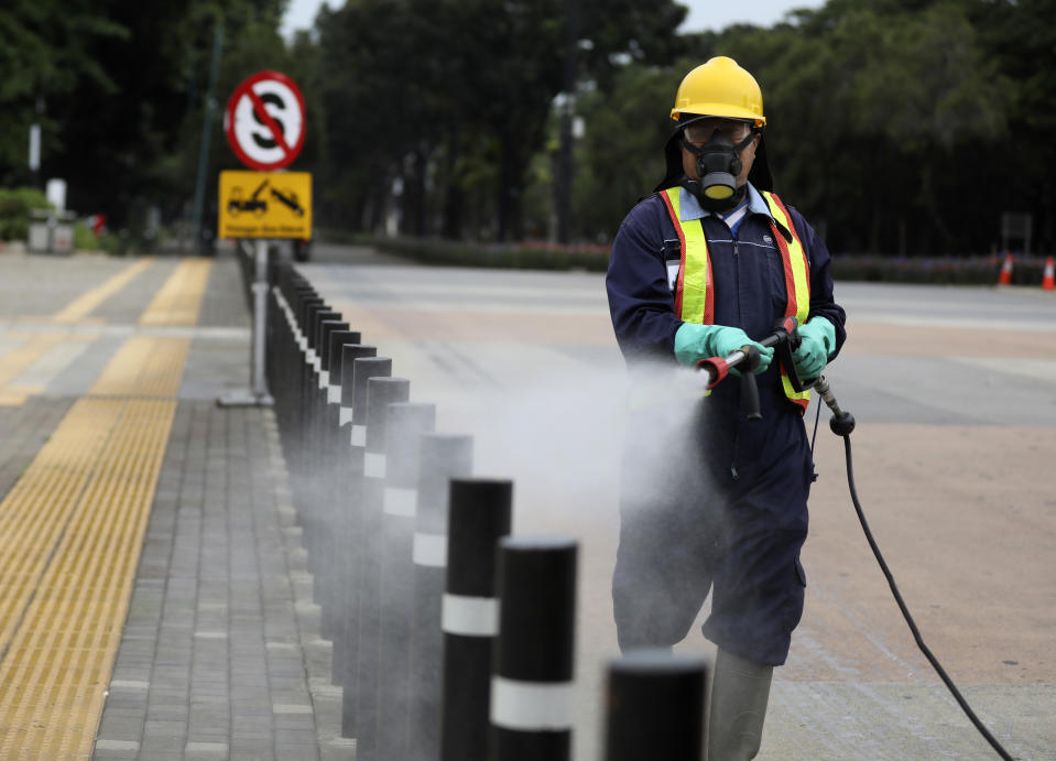 Un operario esparce desinfectante en una acera en el Senayan Sports Complex ante el brote de coronavirus, en Yakarta, Indonesia, el 26 de marzo de 2020. (AP Foto/Dita Alangkara)