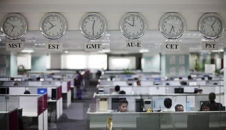 Workers are pictured beneath clocks displaying time zones in various parts of the world at an outsourcing centre in Bengaluru February 29, 2012. REUTERS/Vivek Prakash/Files