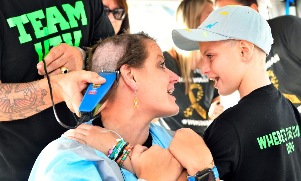 Brittany Sleeth gets her head shaved Sunday minutes after her 7-year-old daughter Vivian's hair was shaved off to prepare for experimental pediatric brain-stem cancer treatment.