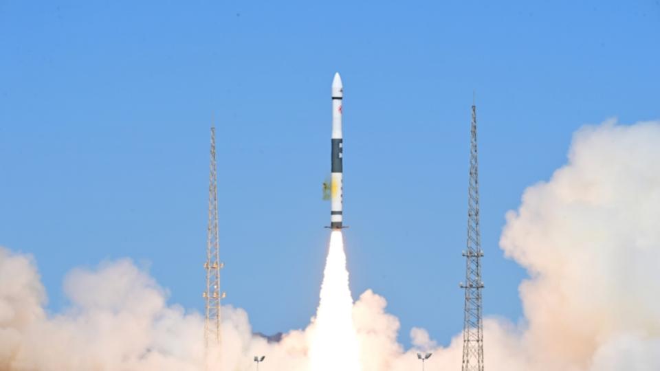 a black and white chinese rocket launches into a blue sky