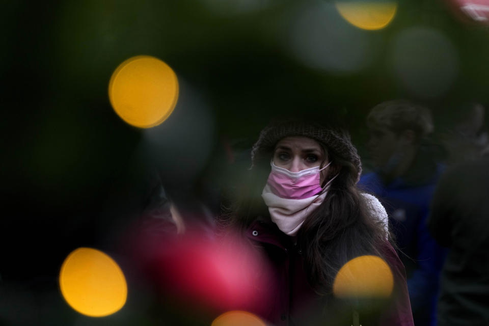 A woman wears a face covering as she walks past a Christmas Lights decoration in London, Wednesday, Dec. 22, 2021. British Prime Minister Boris Johnson said on Monday that his government reserves the "possibility of taking further action" to protect public health as Omicron spreads across the country. (AP Photo/Frank Augstein)