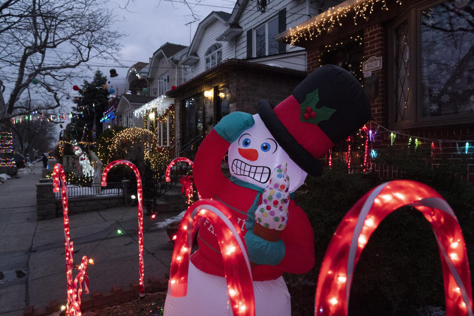 An inflatable snowman and candy canes are part of the decorations that adorn houses in Brooklyn's Dyker Heights neighborhood, Tuesday, Dec. 22, 2020 in New York. Residents are renowned for their displays of over-the-top Christmas light decorations with life-sized Santas, reindeer, toy soldiers, sleighs and snowmen. (AP Photo/Mark Lennihan)