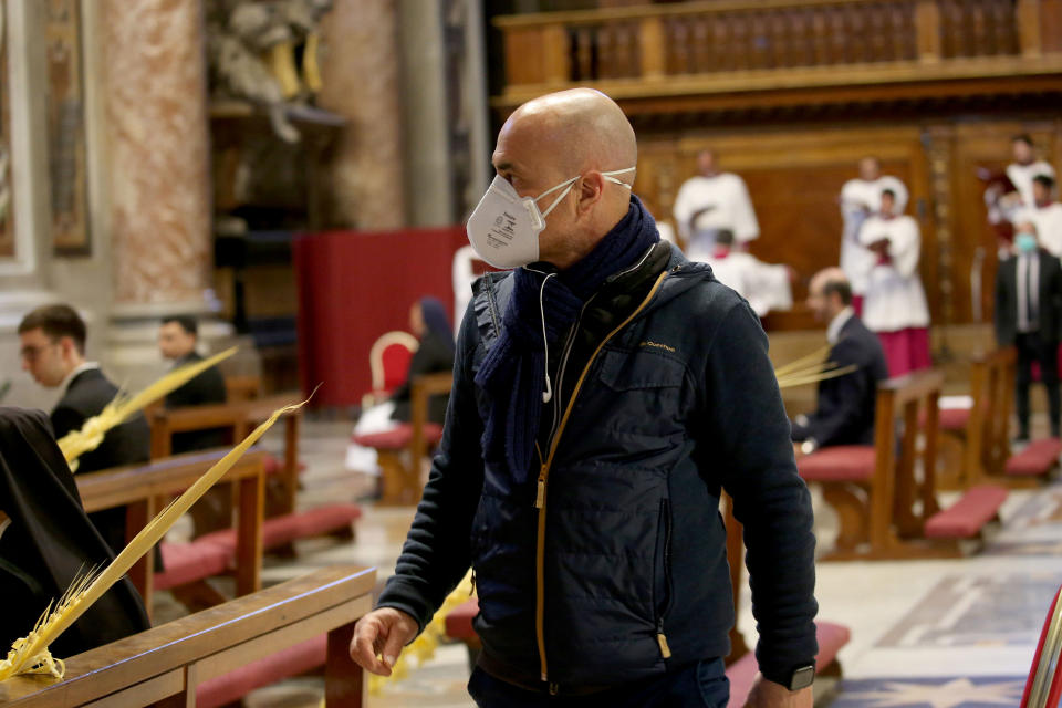 VATICAN CITY, VATICAN - APRIL 05: A Vatican employee wearing a protective mask attends Pope Francis' Palm Sunday Mass in an empty Vatican Basilica of St. Peter's due to the Covid-19 coronavirus pandemic, on April 05, 2020 in Vatican City, Vatican. Pope Francis  greeted the faithful following his Palm Sunday Mass and Angelus and prayed for the sick and their families, and all those who self-sacrificingly care for them. (Photo by Franco Origlia/Getty Images)