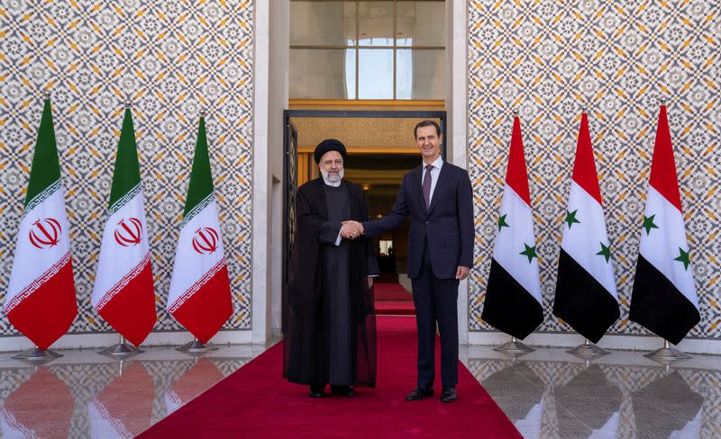Syria's President Bashar al-Assad stands with Iranian President Ebrahim Raisi in Damascus