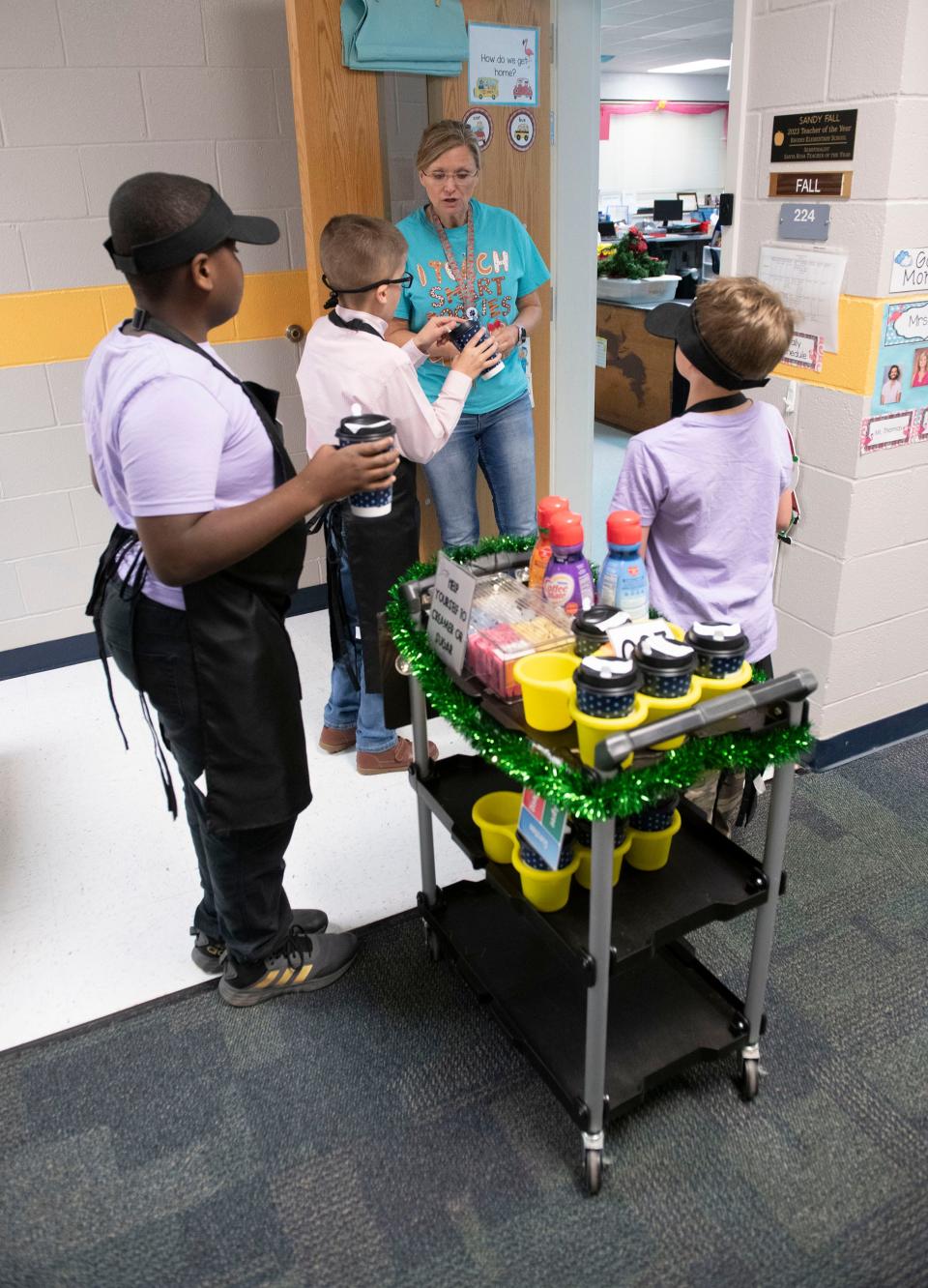 Flying Squirrel Cafe employees deliver beverages to Rhodes Elementary School teacher Sandy Fall on Friday, Dec. 1, 2023. A select group of Rhodes students operates the Flying Squirrel to help them learn life and social skills by participating in running the business.