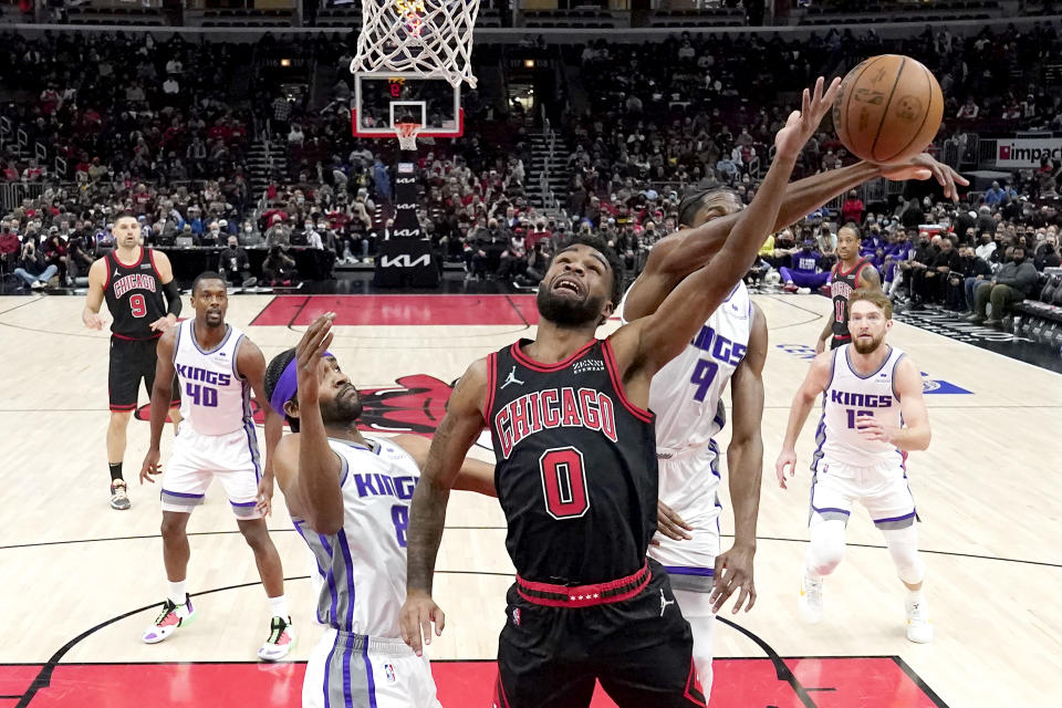 Sacramento Kings' Justin Holliday (9) blocks the shot of Chicago Bulls' Coby White Maurice Harkless, left, fouled White during the first half of an NBA basketball game Wednesday, Feb. 16, 2022, in Chicago. (AP Photo/Charles Rex Arbogast)