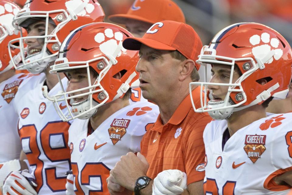 Clemson head coach Dabo Swinney, second from right, walks with his players onto the field.