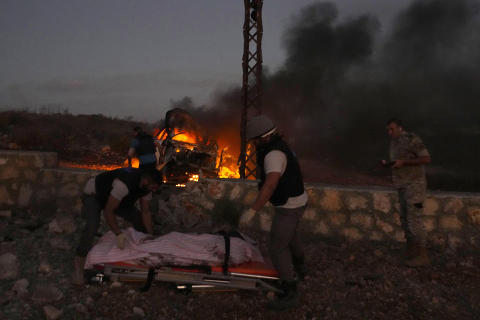 Civil Defense workers remove the dead body of a journalist killed by Israeli shelling, at Alma al-Shaab border village with Israel, south Lebanon, Friday, Oct. 13, 2023. An Israeli shell landed in a gathering of international journalists covering clashes on the border in south Lebanon, killing one and leaving six others injured. (AP Photo/Hassan Ammar)