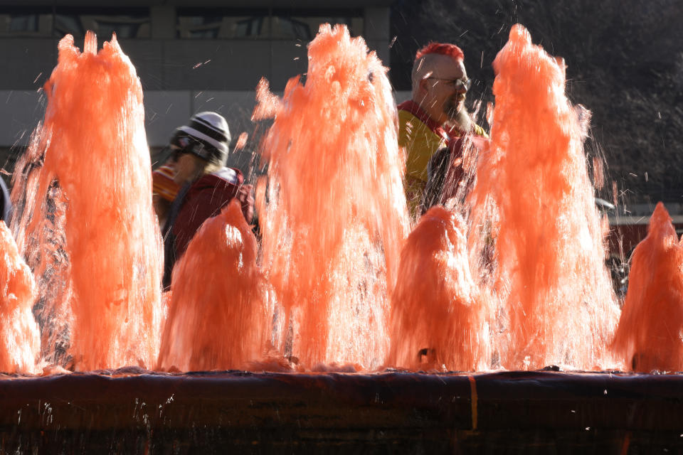 Los fans pasan junto a una fuente con agua roja cuando llegan al desfile de la victoria de los Kansas City Chiefs en Kansas City, Missouri. (AP Photo/Charlie Riedel)