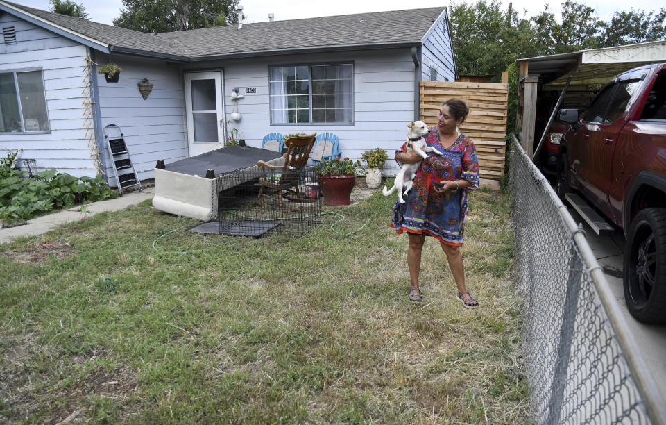 Lucy Molina stands in her front yard in Commerce City, Colo., on Tuesday, July 25, 2023. Without central air conditioning, the single mother's home in one of the Denver metro's poorest areas has reached 107 degrees Fahrenheit (41.7 Celsius), she said. America's poorest residents and people of color are far more likely to face grueling heat without air conditioning to keep their body temperatures down, according to a Boston University analysis of 115 U.S. cities. (AP Photo/Thomas Peipert)