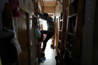 Simon Wong, 64, climbs out of his 2 square metre subdivided residential unit, known as a "coffin home", following the outbreak of the new coronavirus, in Hong Kong