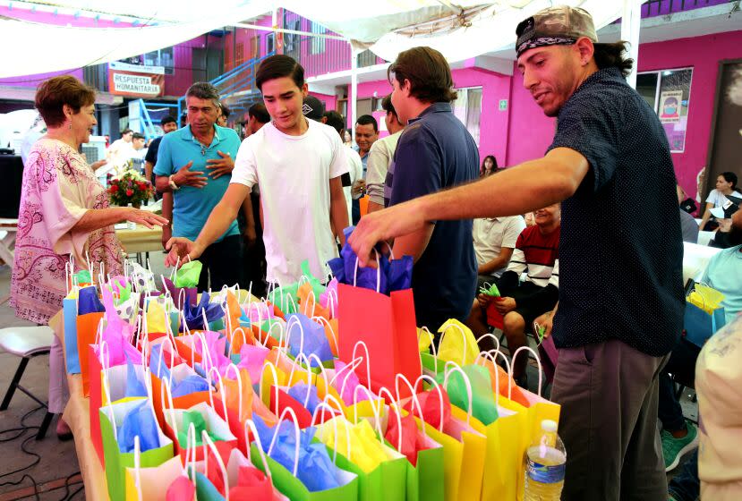 Refugee Juan Carlos Manzo Manzo, right, grabs one of the gift bags each father received for Father's Day at refugee shelter Cobina Posada Del Migrante in Mexicali, Mexico, on Saturday, June 24, 2023. The shelter, five minutes from the Mexico/USA border, houses families who are waiting for their refugee applications to be processed in the United States.