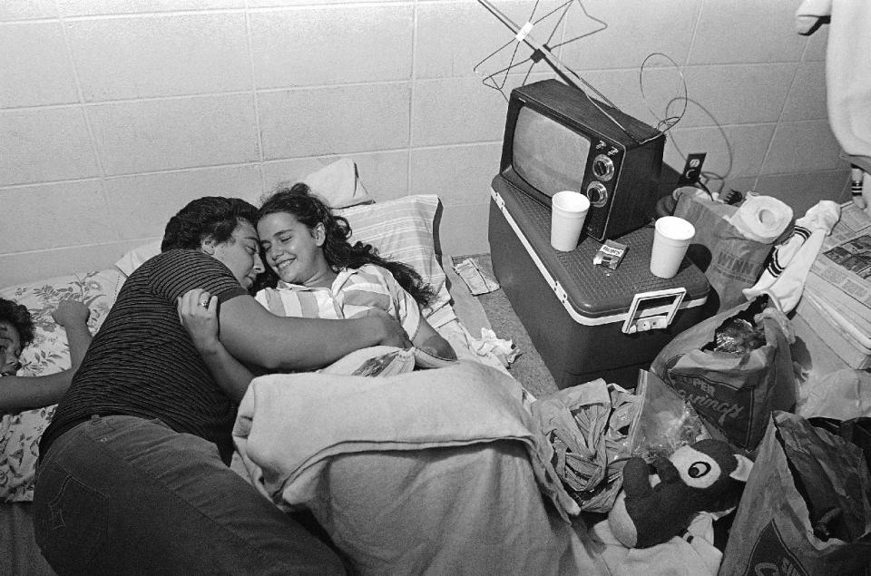 FILE - In this Friday, Aug. 30, 1985, file photo taken by Dave Martin, Mark Bailey holds his fiance Belinda Mammack as they relax in an emergency shelter at Theodore High School, Ala. Martin, a longtime Associated Press photographer based in Montgomery, Ala., died after collapsing on the Georgia Dome field at the Chick-fil-A Bowl on Tuesday, Dec. 31, 2013. Martin was 59. (AP Photo/Dave Martin, File)